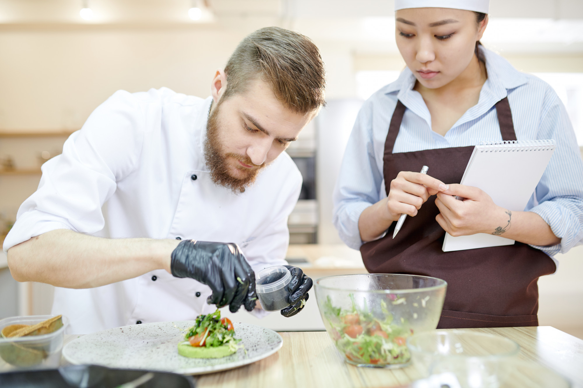 consultant reviewing plated meals with chef in modern kitchen
